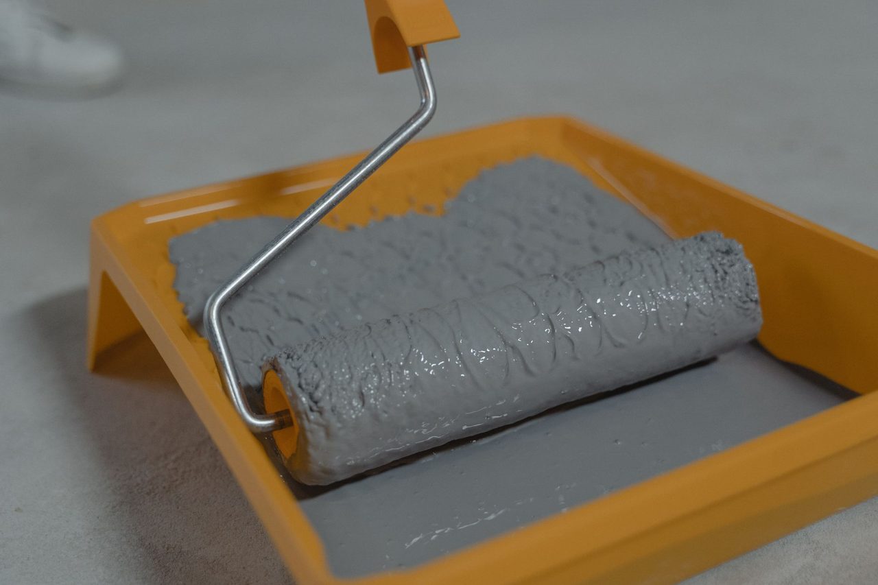 Detailed view of a gray paint roller placed in an orange tray, ready for painting.